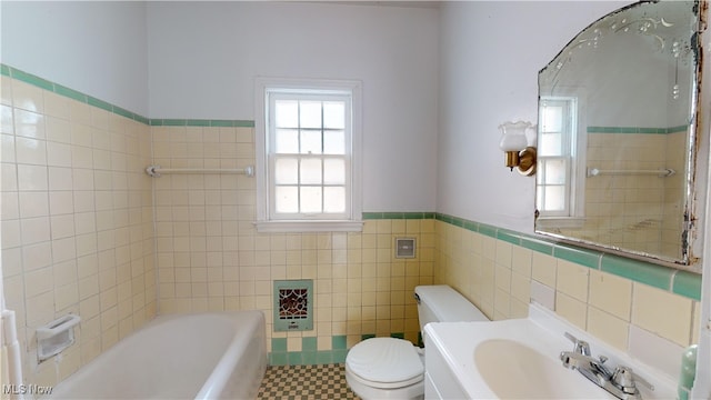 bathroom featuring a tub to relax in, sink, tile patterned floors, tile walls, and toilet