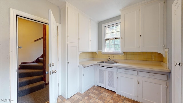 kitchen featuring white cabinets, tasteful backsplash, sink, and light tile patterned flooring