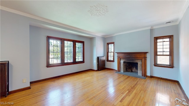 unfurnished living room with a wealth of natural light, crown molding, and light hardwood / wood-style floors