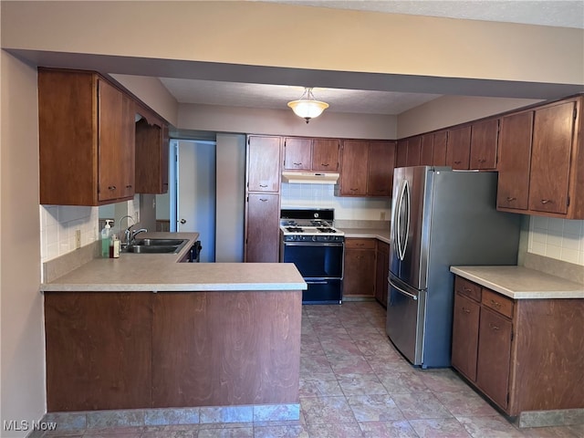 kitchen featuring sink, tasteful backsplash, range with gas stovetop, and stainless steel refrigerator