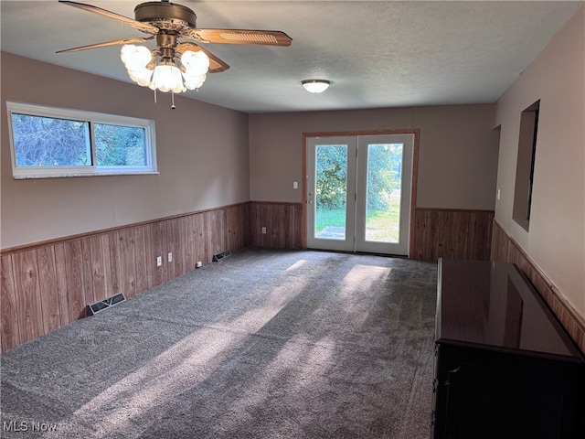 spare room with a textured ceiling, ceiling fan, french doors, and carpet