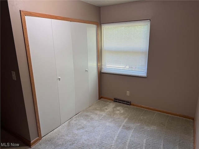 unfurnished bedroom featuring light colored carpet and a closet