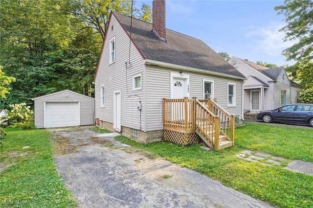 view of front of house featuring a garage, a front yard, and an outbuilding