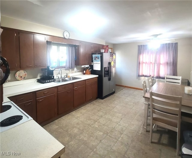 kitchen featuring light tile patterned floors, sink, stainless steel fridge, and white electric stovetop