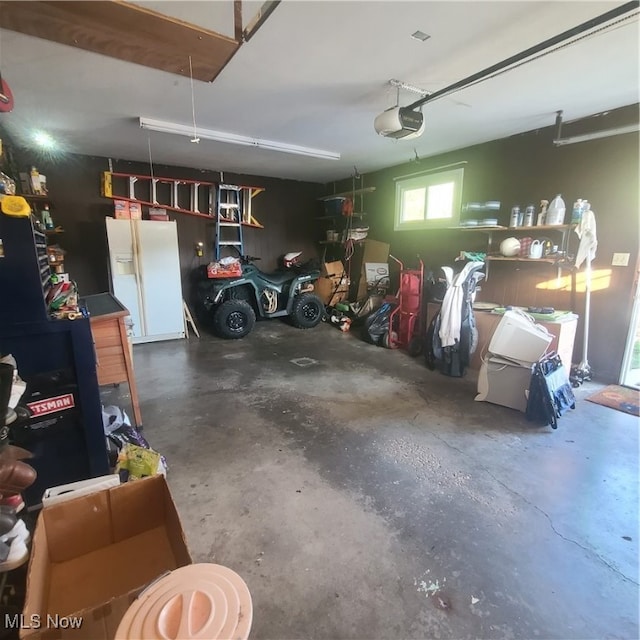 garage featuring a garage door opener and white fridge with ice dispenser