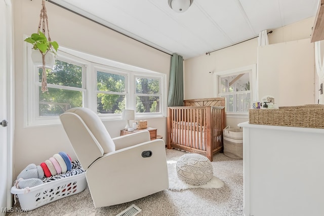 carpeted bedroom featuring multiple windows and a crib