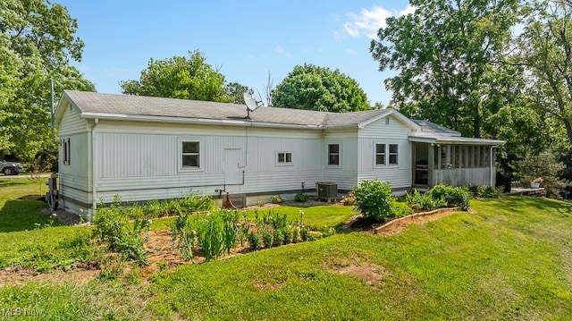 rear view of house with a yard, cooling unit, and a sunroom