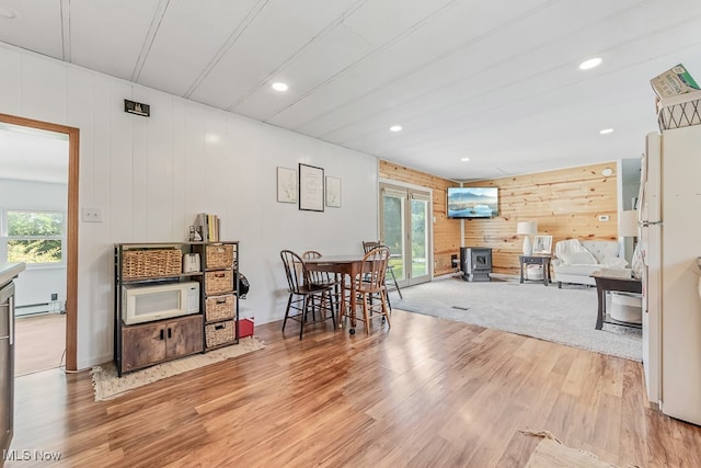 dining space with wood-type flooring, a healthy amount of sunlight, and wooden walls