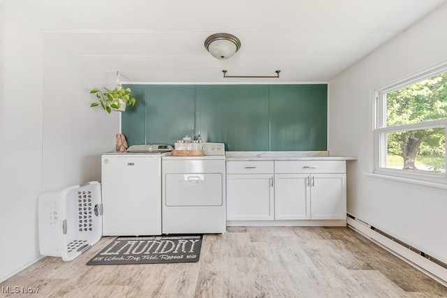 laundry room with a baseboard heating unit, light hardwood / wood-style floors, cabinets, and separate washer and dryer