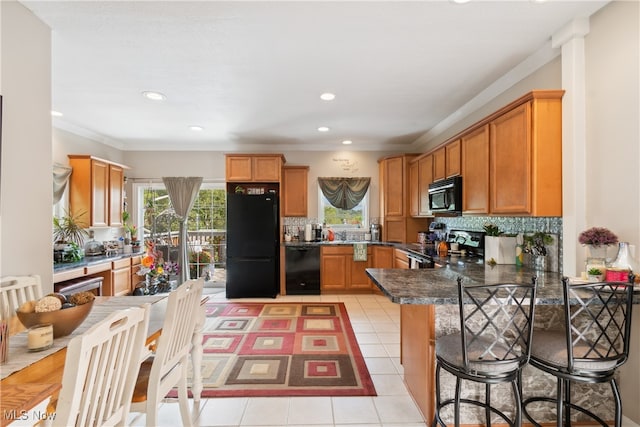 kitchen with kitchen peninsula, black appliances, light tile patterned floors, and tasteful backsplash