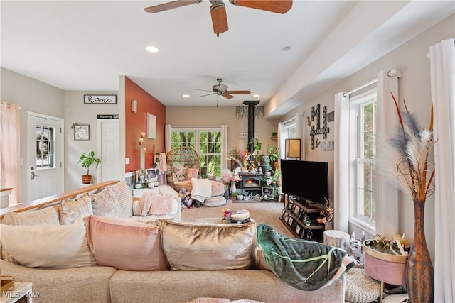 living room with carpet flooring, ceiling fan, and a wood stove