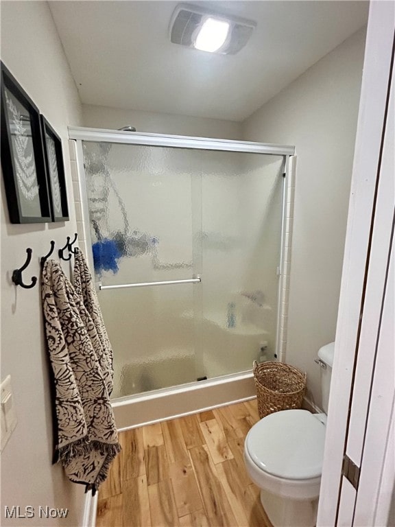 bathroom featuring toilet, hardwood / wood-style flooring, and a shower with door