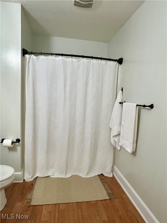 bathroom with toilet, hardwood / wood-style floors, and a textured ceiling