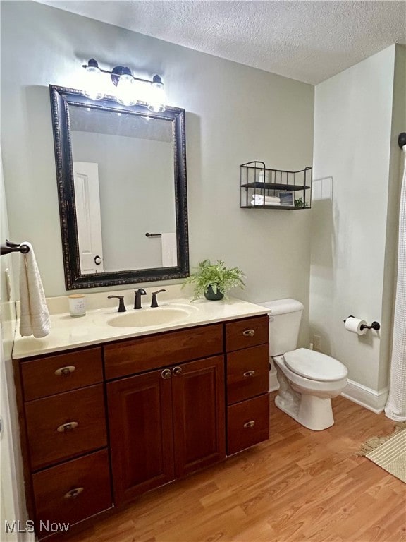 bathroom with vanity, toilet, hardwood / wood-style floors, and a textured ceiling