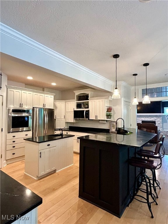 kitchen with light wood-type flooring, ornamental molding, stainless steel appliances, and a large island