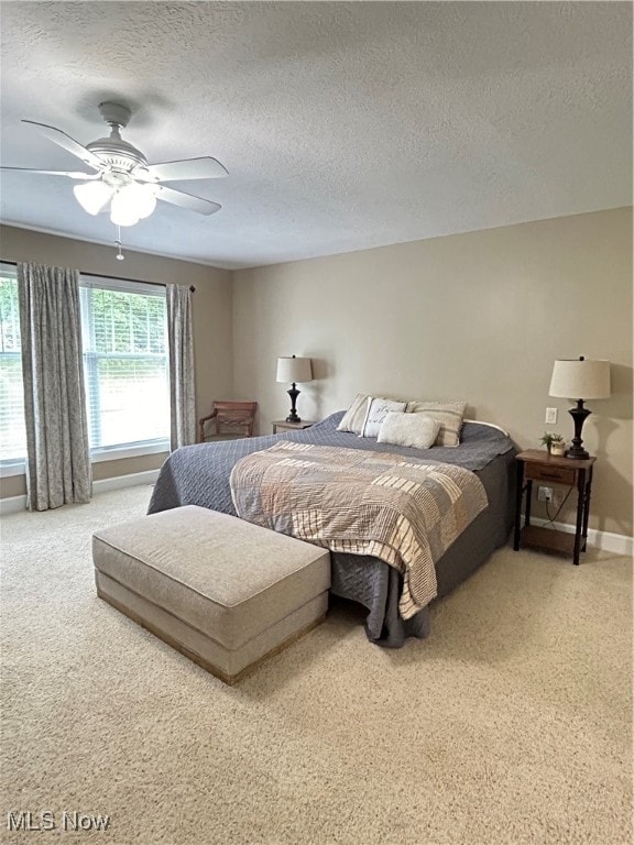 carpeted bedroom featuring ceiling fan and a textured ceiling