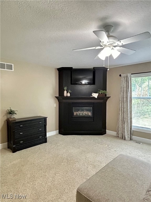 unfurnished living room featuring a textured ceiling, ceiling fan, and carpet floors