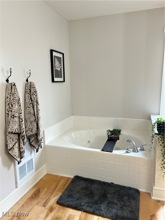 bathroom featuring hardwood / wood-style floors and a relaxing tiled tub