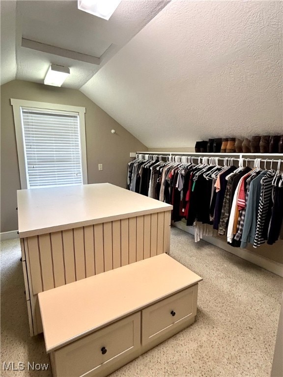 spacious closet with lofted ceiling and light carpet