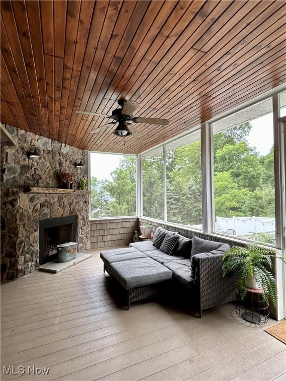 sunroom with wood ceiling, ceiling fan, a wealth of natural light, and a fireplace