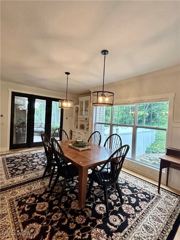 dining space featuring ornamental molding, french doors, and a notable chandelier