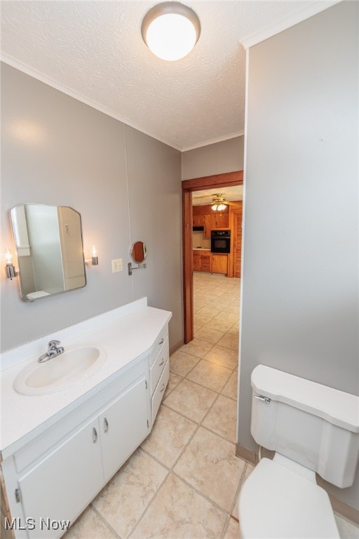 bathroom with toilet, crown molding, vanity, a textured ceiling, and ceiling fan