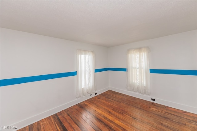 empty room with a textured ceiling and wood-type flooring