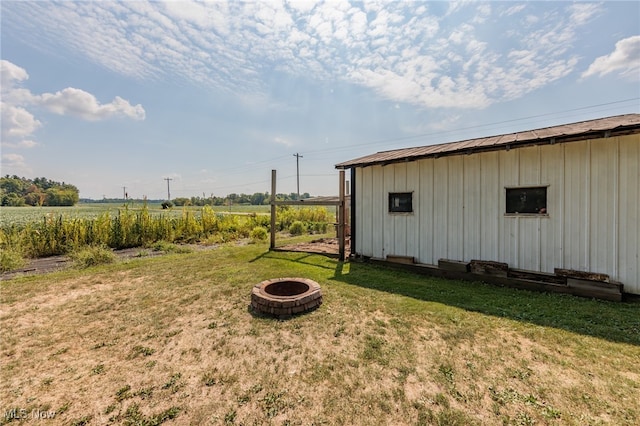 view of yard with an outdoor fire pit and a rural view