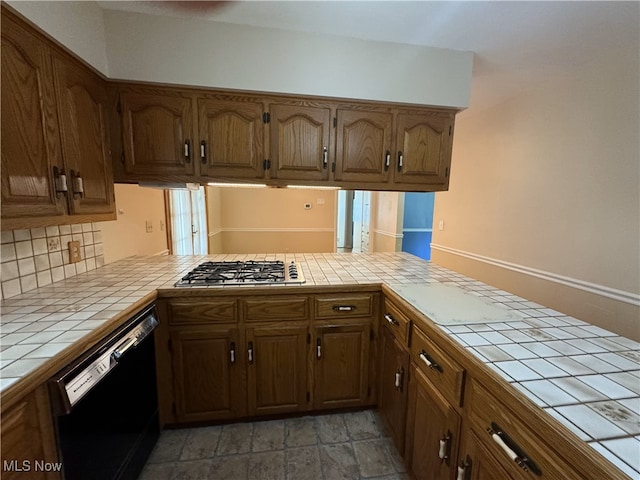 kitchen with stainless steel gas cooktop, backsplash, tile counters, kitchen peninsula, and black dishwasher