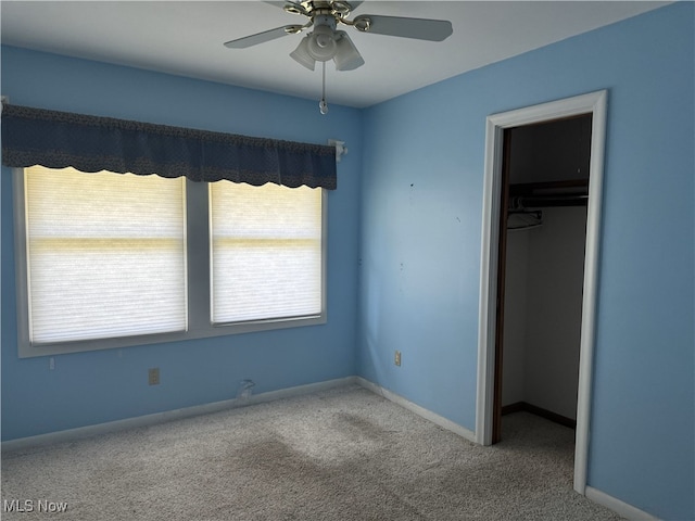 unfurnished bedroom featuring a closet, carpet flooring, a walk in closet, and ceiling fan