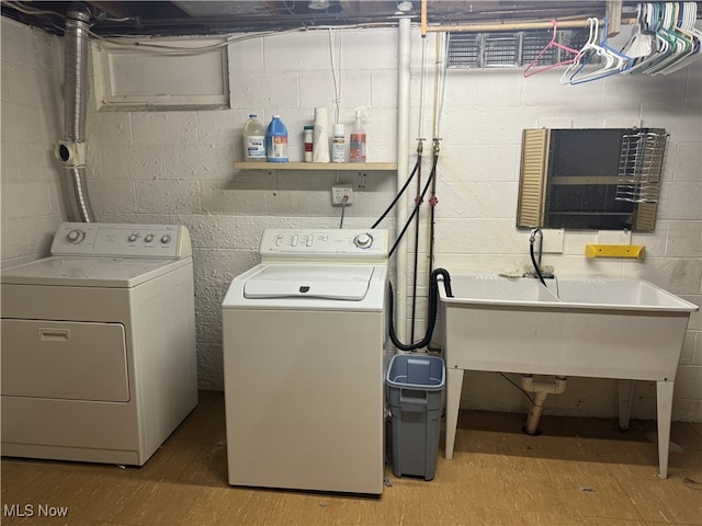 clothes washing area with light hardwood / wood-style flooring, washing machine and dryer, and sink