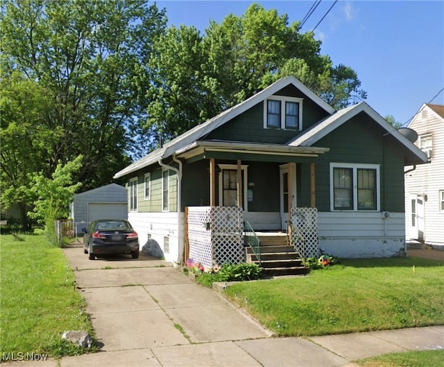 bungalow-style house featuring a garage, a front yard, a porch, and an outbuilding