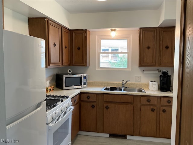 kitchen with white appliances, light hardwood / wood-style floors, and sink