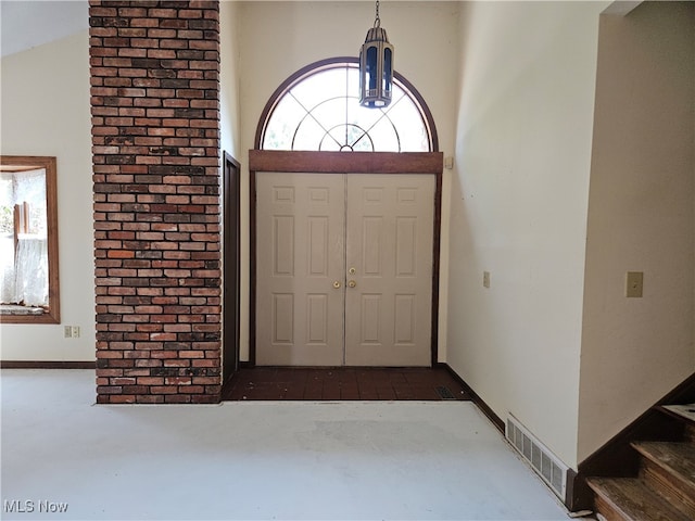 entrance foyer with a wealth of natural light, brick wall, and lofted ceiling