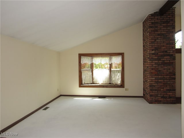 spare room with lofted ceiling, brick wall, and carpet