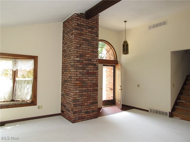 unfurnished living room featuring brick wall and beam ceiling