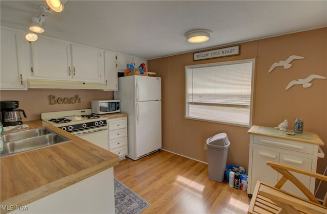 kitchen featuring white appliances, sink, white cabinetry, and light hardwood / wood-style flooring