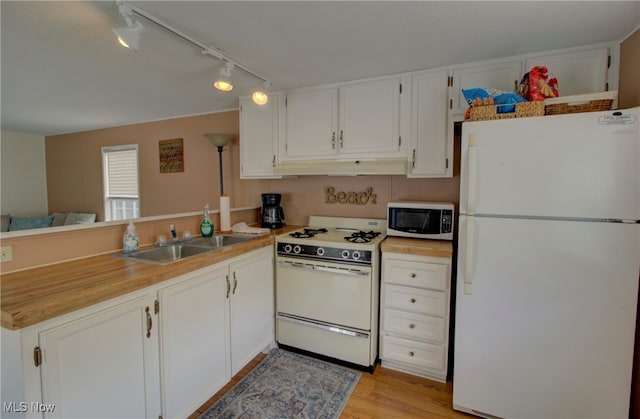 kitchen featuring white appliances, sink, light wood-type flooring, white cabinets, and track lighting