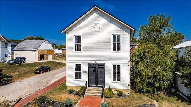 traditional-style house with an outbuilding, a detached garage, and a front yard