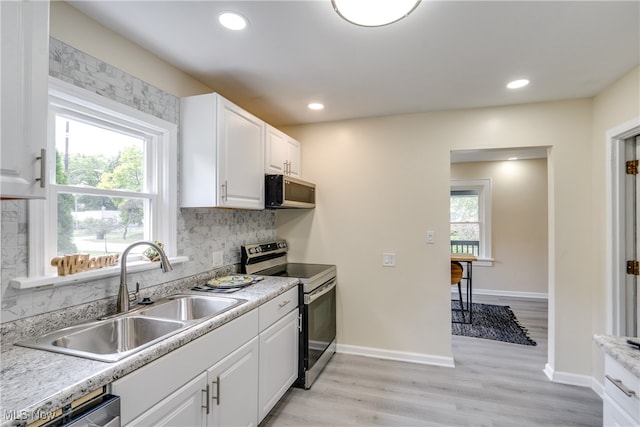 kitchen featuring plenty of natural light, stainless steel electric range oven, and white cabinetry