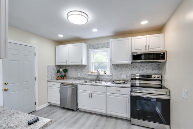 kitchen featuring light hardwood / wood-style flooring, backsplash, sink, appliances with stainless steel finishes, and white cabinets