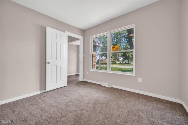 spare room with carpet flooring, baseboards, and visible vents