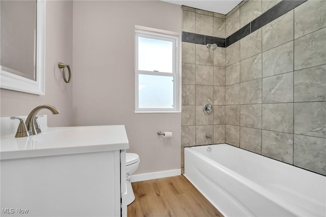 bathroom with vanity, wood finished floors, baseboards, tub / shower combination, and toilet