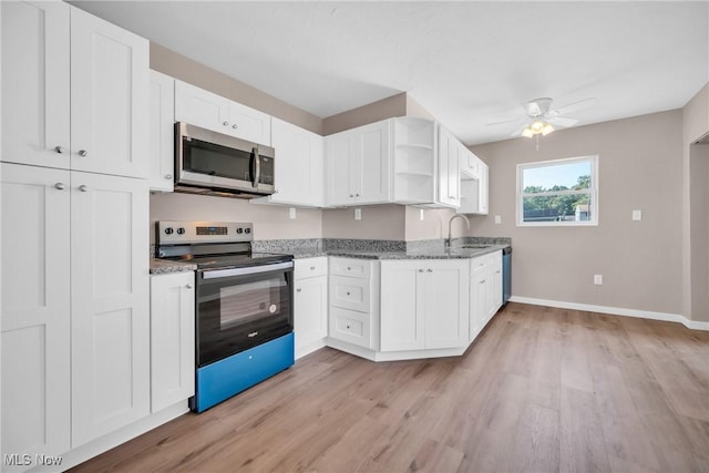 kitchen with open shelves, light wood-style flooring, dark stone counters, white cabinets, and appliances with stainless steel finishes