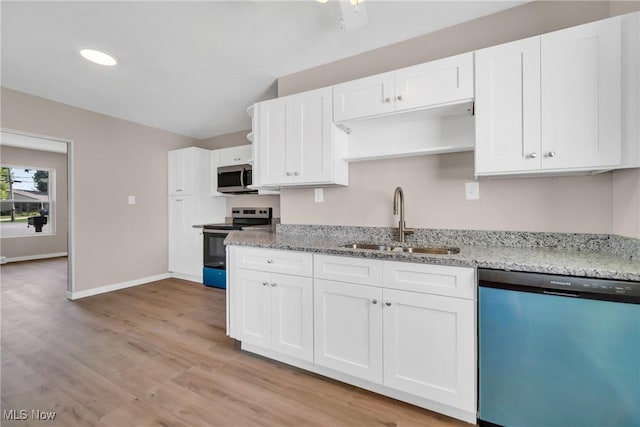 kitchen featuring light wood-type flooring, a sink, white cabinetry, appliances with stainless steel finishes, and light stone countertops