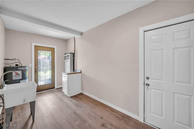 foyer with light wood-type flooring, baseboards, and water heater