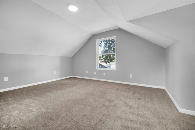 additional living space featuring carpet flooring, baseboards, and vaulted ceiling