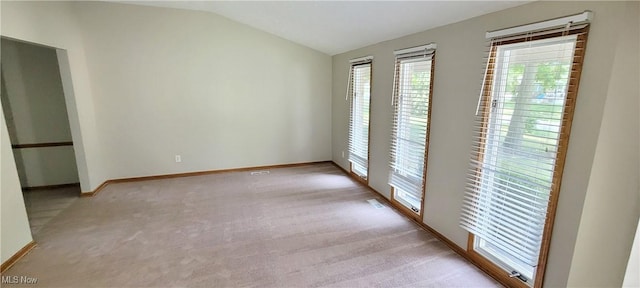 unfurnished room with lofted ceiling, light carpet, and baseboards