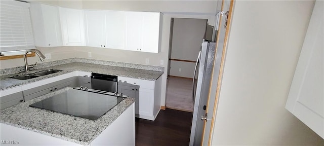 kitchen with light stone counters, black electric stovetop, dark wood-type flooring, a sink, and white cabinetry