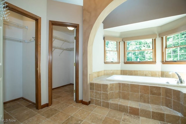 bathroom featuring tiled bath and plenty of natural light